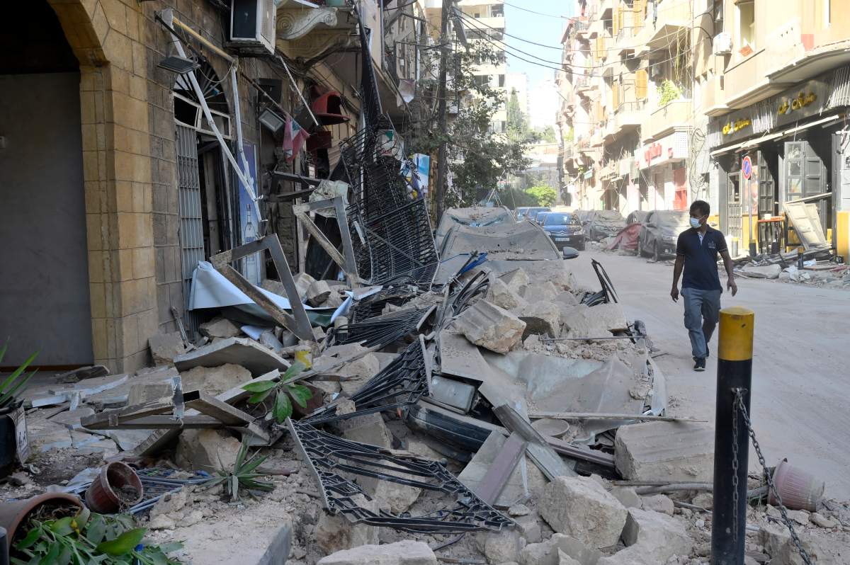 A man walks next to damaged vehicles in the aftermath of a massive explosion in Beirut, Lebanon, 05 August 2020. According to media reports, at least 100 people were killed and more than 4,000 were injured after an explosion, caused by over 2,500 tonnes of ammonium nitrate stored in a warehouse, devastated the port area on 04 August.
