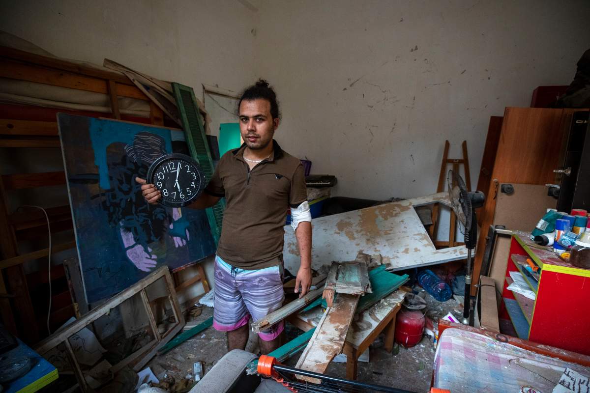 Hasan Al Armali, holds a wall clock that was stoped working at the time of the Tuesday’s explosion in the seaport of Beirut, poses for a photograph at his bedroom inside his destroyed apartment, in Beirut , Lebanon, Aug. 6, 2020.