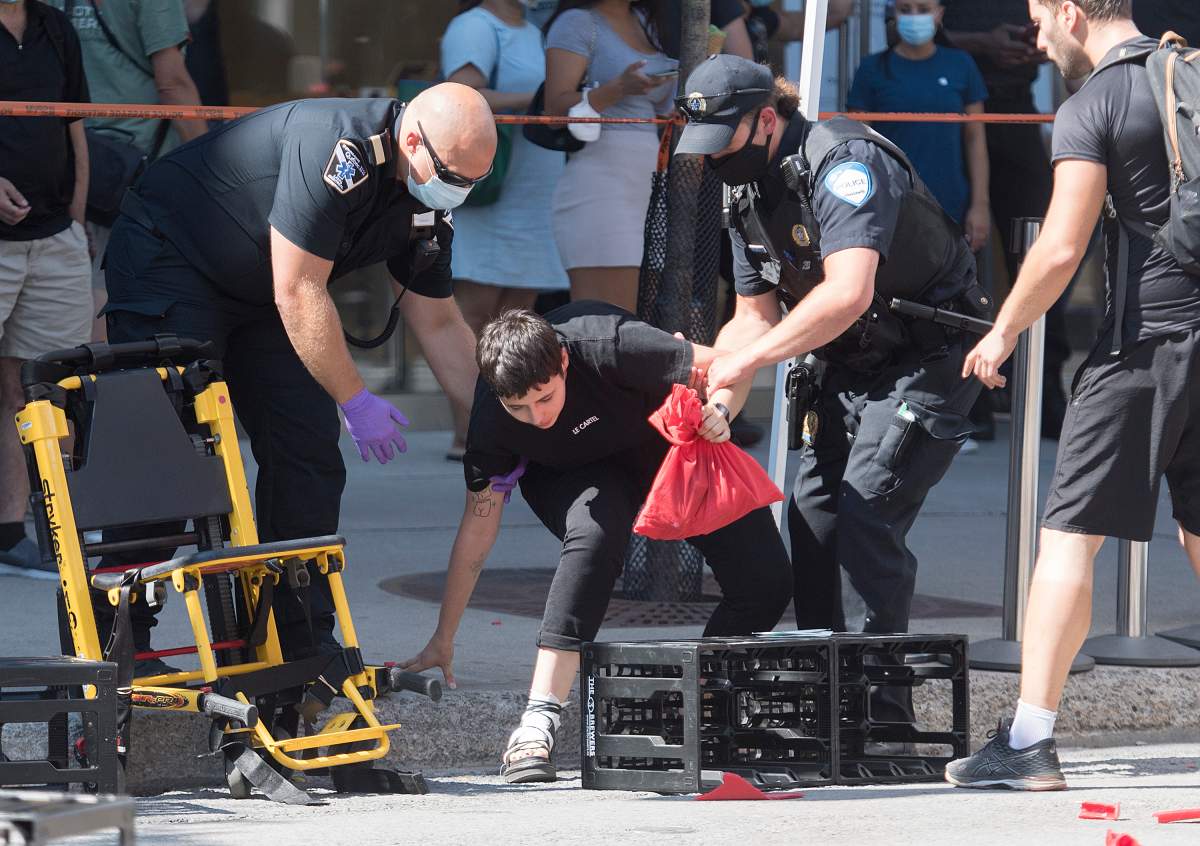 A person is helped by first responders after a jeep sped down a pedestrian zone on Sainte-Catherine Street in Montreal, Saturday, Aug. 8, 2020.