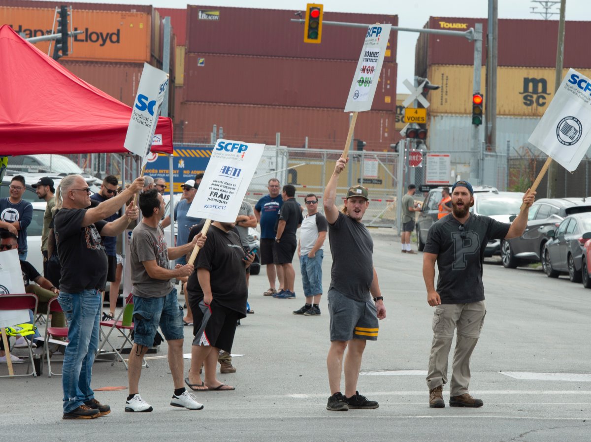 Striking workers picket in front of the Port of Montreal, in Montreal, Monday, Aug. 10, 2020. The workers have been without a contract for over two years.