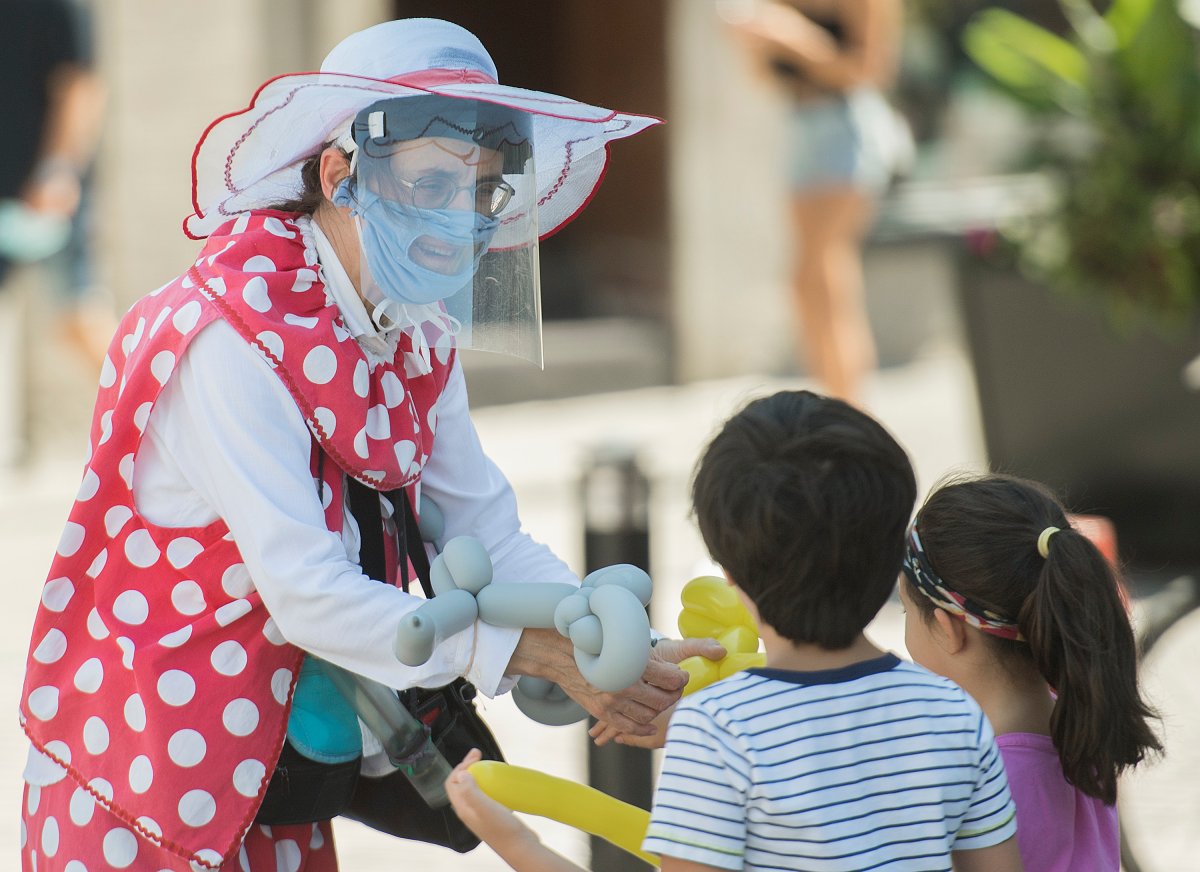 A clown makes balloon-shaped animals for children in the Old Port of Montreal, Sunday, Aug. 16, 2020, as the COVID-19 pandemic continues in Canada and around the world. 