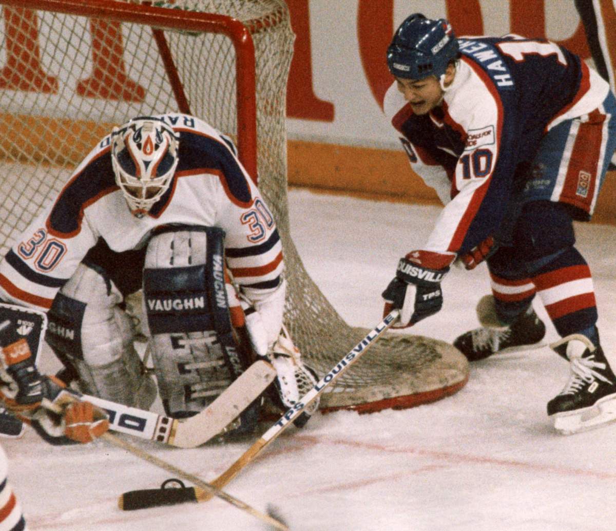 Winnipeg Jets' Dale Hawerchuk tries a wraparound move on Edmonton Oilers' Bill Ranford  during NHL action in Edmonton on April 4, 1990. 