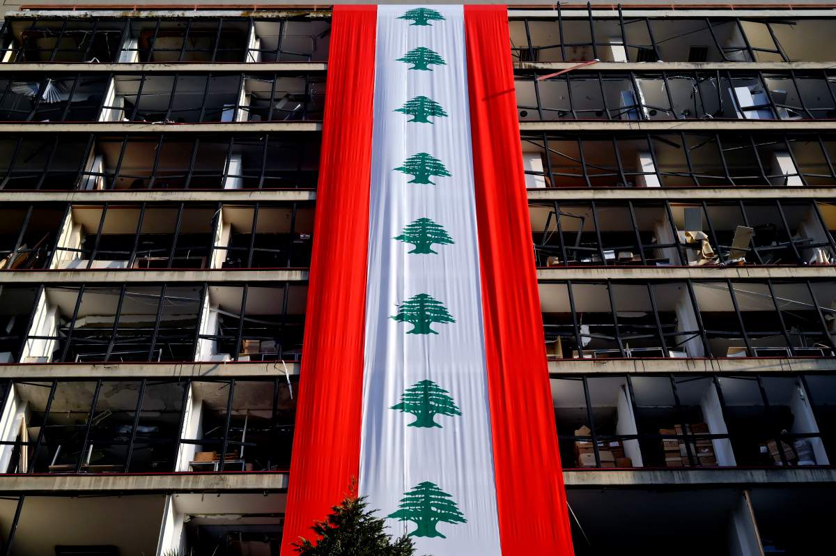 epa08614906 A Lebanese flag hangs on a damaged building near the devastated harbor area after the explosion that hit Beirut port, in Beirut, Lebanon, 20 August 2020. According to Lebanese Health Ministry at least 179 people were killed, and more than 6000 injured 49 missing in the Beirut blast that devastated the port area on 04 August and believed to have been caused by an estimated 2,750 tons of ammonium nitrate stored in a warehouse. EPA/WAEL HAMZEH.