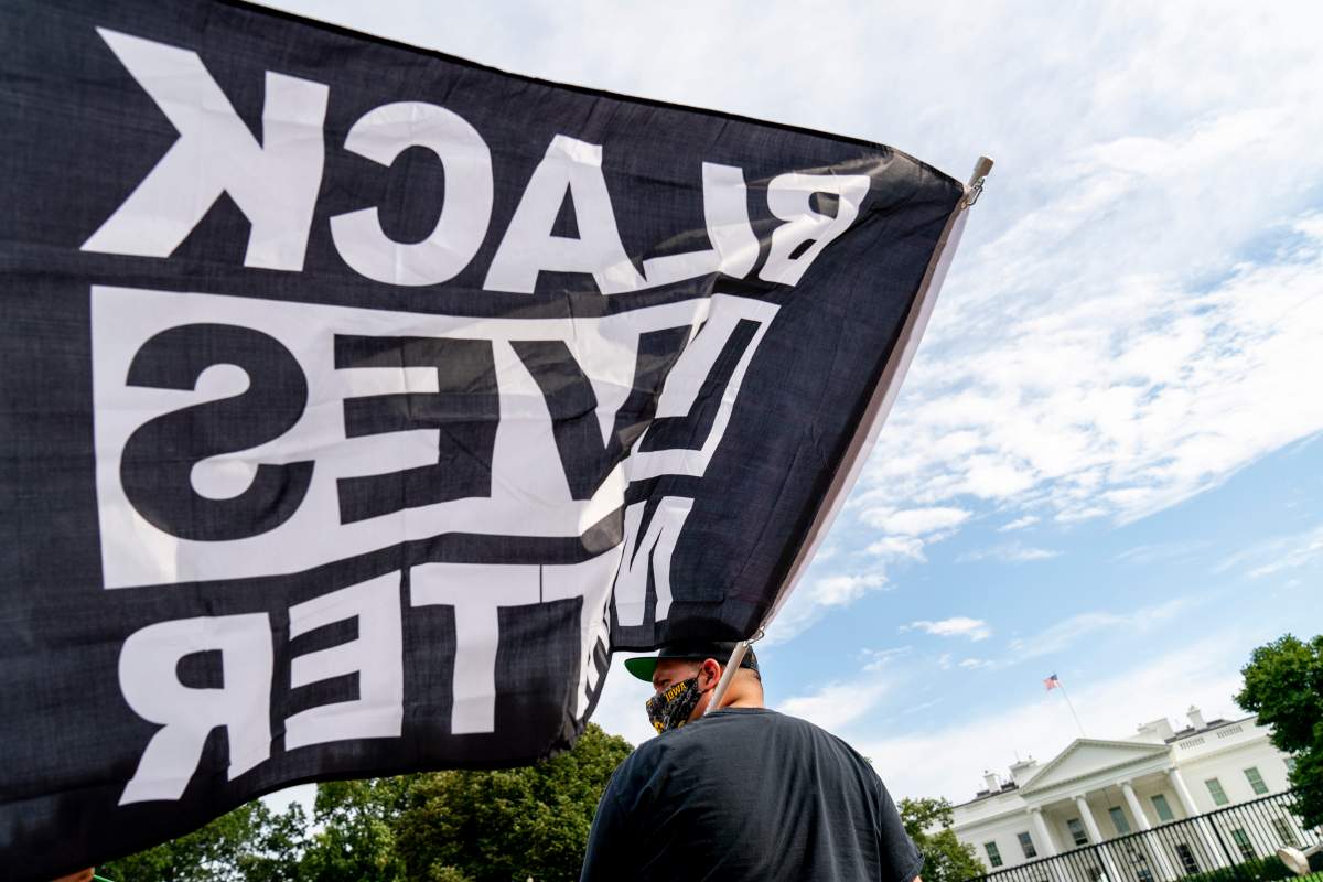 A man carries a Black Lives Matter flag in Lafayette Square outside the White House on the fourth night of the Republican National Convention, Thursday, Aug. 27, 2020, in Washington.
