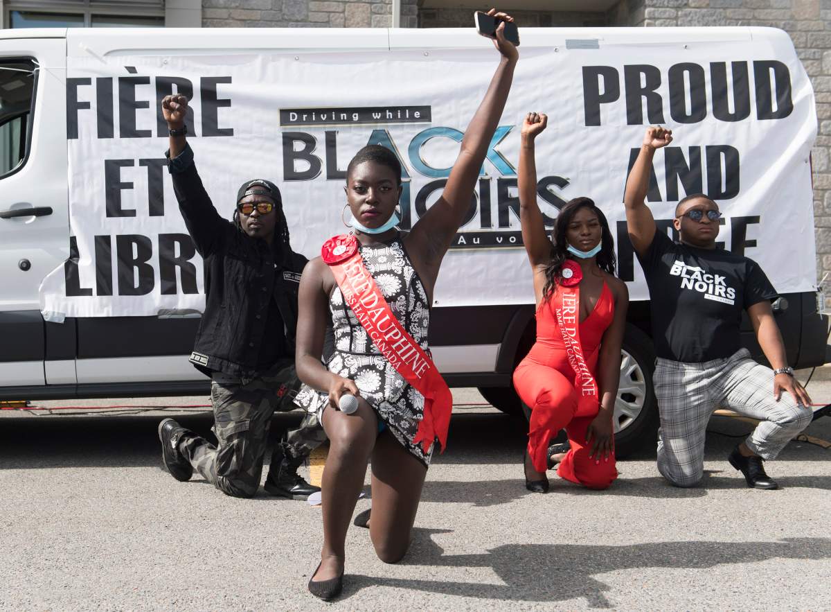 Demonstrators take a knee outside the constituency office of Quebec Premier Francois Legault during a Driving While Black protest in L'Assomption, Que., Sunday, Aug. 30, 2020. \.