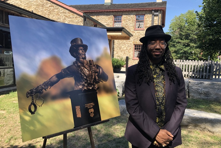 Quentin VerCetty poses beside a picture of his winning proposal for the Joshua Glover memorial.