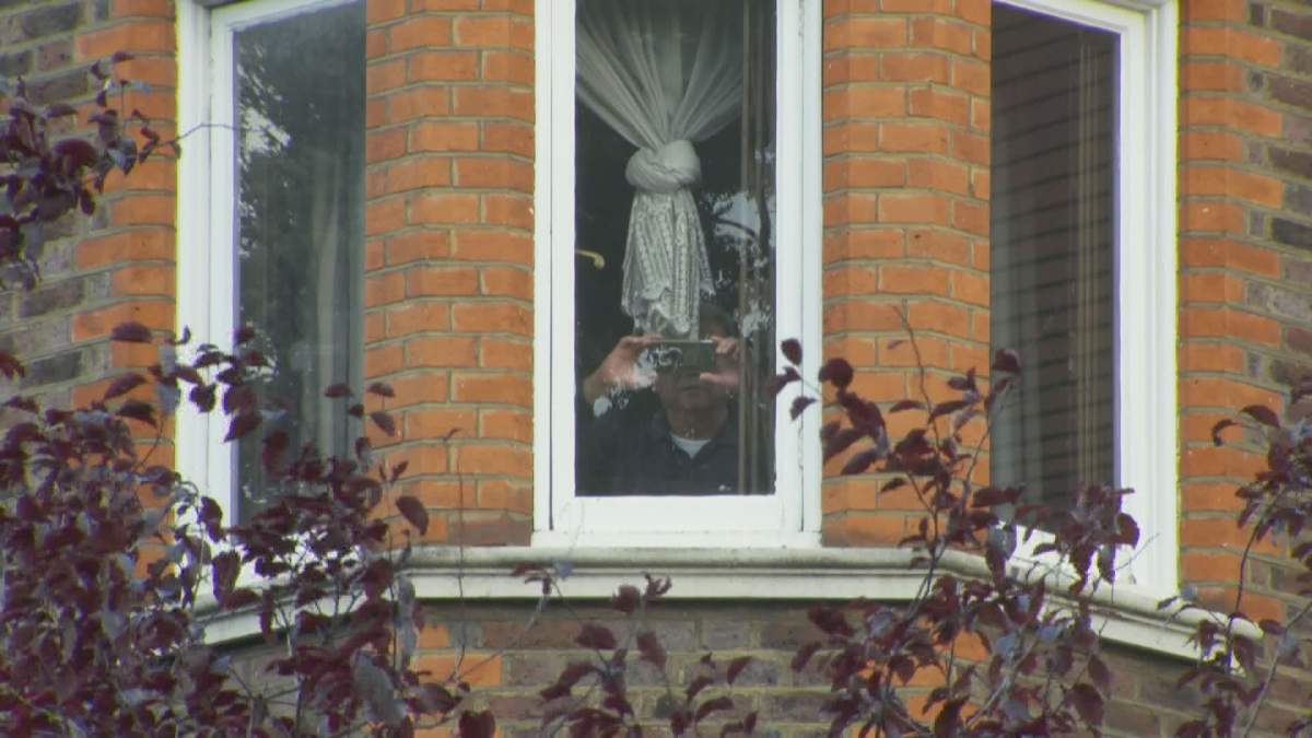 A person inside the Cultural Section of the Chinese Embassy to the U.K. films a group of nine protesters and a Global News film crew in Hampstead, London, England on Aug. 25, 2020. (Braden Latam / Global News).