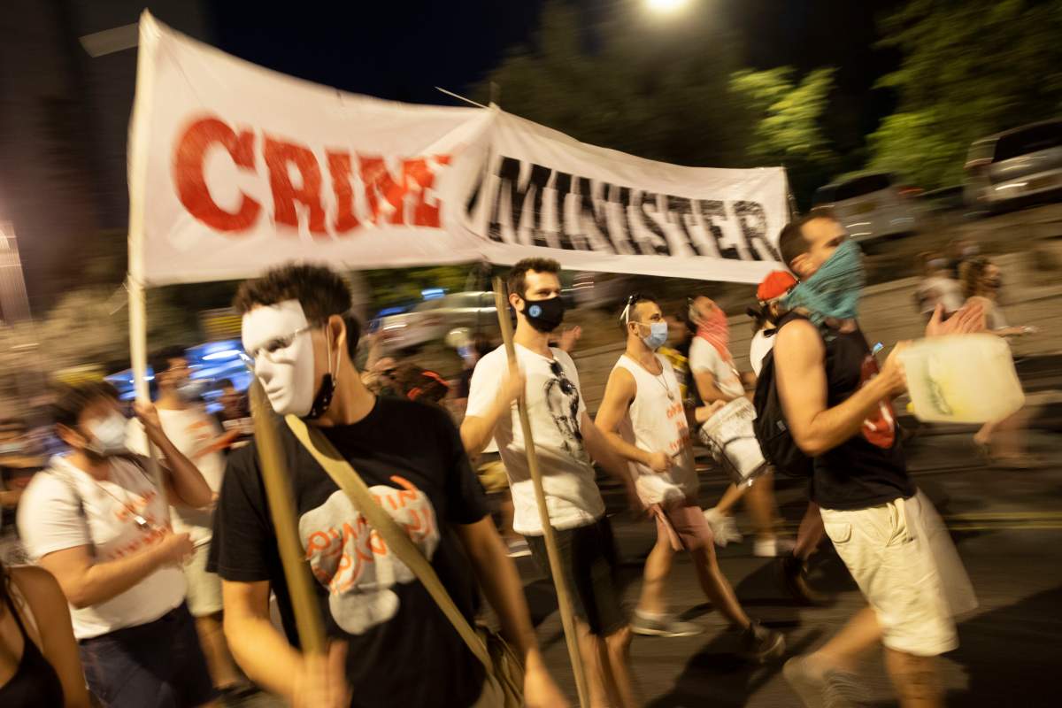Demonstrators chant slogans and hold signs during a rally against Israel’s Prime Minister Benjamin Netanyahu outside his residence in Jerusalem, Saturday, Aug 1, 2020. Protesters demanded that the embattled Israeli leader to resign as he faces a trial on corruption charges and grapples with a deepening coronavirus crisis.