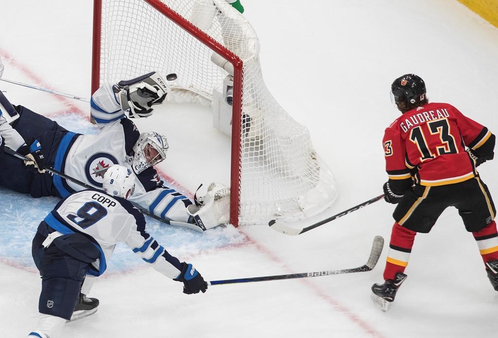 Winnipeg Jets goalie Connor Hellebuyck (37) is scored on by the Calgary Flames' Johnny Gaudreau (13) as the Jets' Andrew Copp defends during second-period NHL qualifying round game action in Edmonton, on Saturday, Aug. 1, 2020.