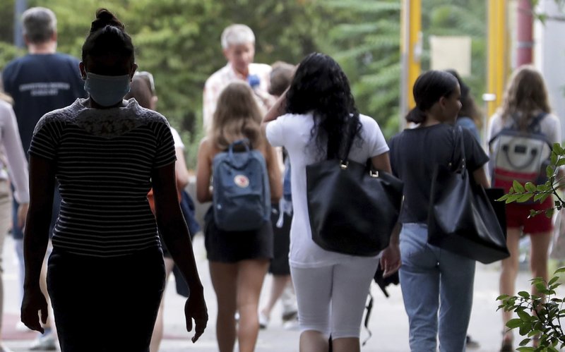 FILE -- Students arrive at the 'Friedensburg Oberschule' school for the first day at school after the summer vacations during the new coronavirus outbreak in Berlin, Germany, Monday, Aug. 10, 2020. Many around the world will be closely observing the real-life experiment offered in Germany to see what works and what doesn't. At least 41 schools in Berlin have reported that students or teacher have become infected with the new coronavirus, not even two weeks after schools reopened in the German capital. (AP Photo/Michael Sohn)
.