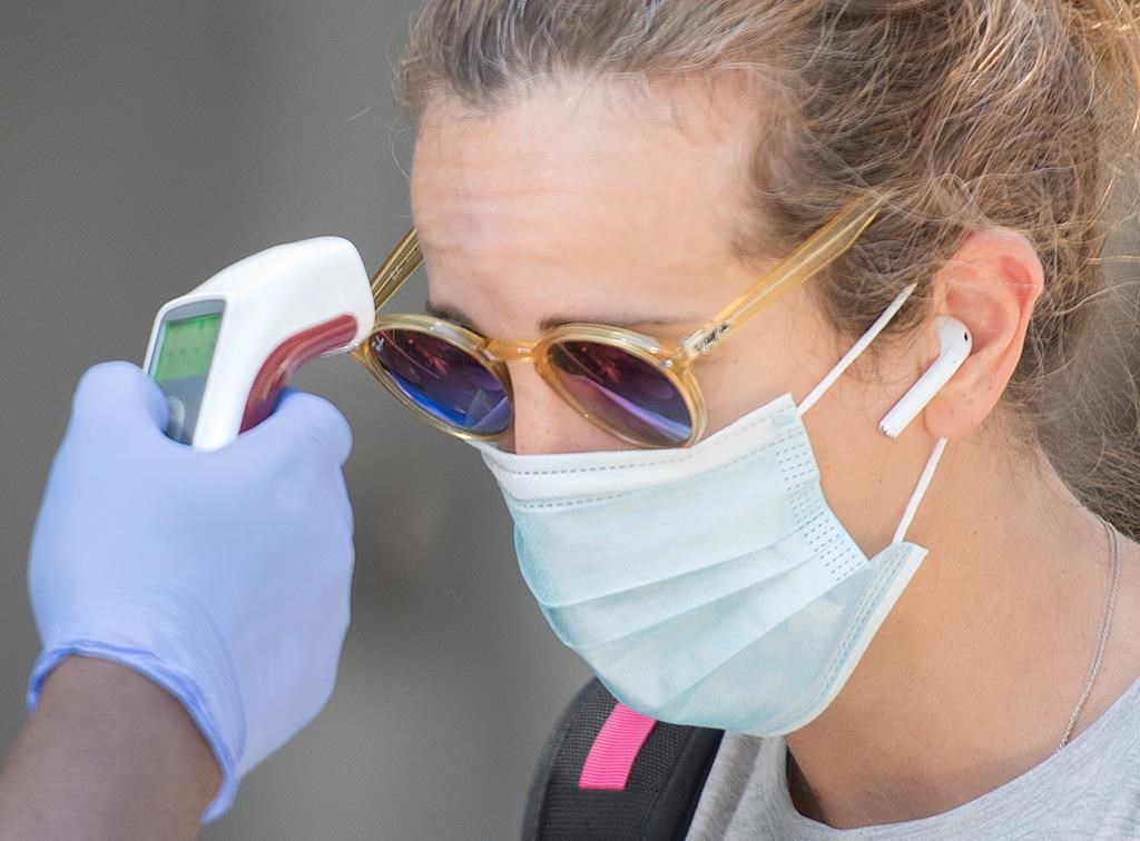 A woman has her temperature checked prior to entering a store in Montreal, Saturday, Aug. 1, 2020.
