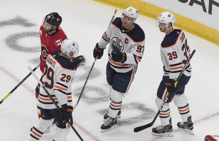 Edmonton Oilers’ Leon Draisaitl (29), Connor McDavid (97) and Alex Chiasson (39) celebrate a goal as Calgary Flames’ Derek Forbort (20) skates by during first period NHL exhibition game action in Edmonton on Tuesday, July 28, 2020.