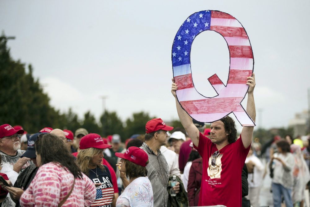 David Reinert holding a Q sign waits in line with others to enter a campaign rally with President Donald Trump and U.S. Senate candidate Rep. Lou Barletta, R-Pa., Thursday, Aug. 2, 2018, in Wilkes-Barre, Pa.