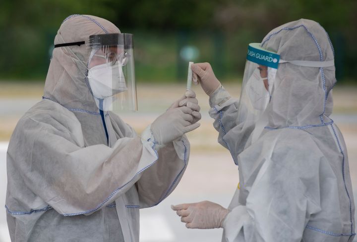 Health professionals wearing protective gear, face shield and face mask label a saliva sample at a drive-in COVID-19 testing facility in Berlin on April 30, 2020, amid the new coronavirus COVID-19 pandemic.  