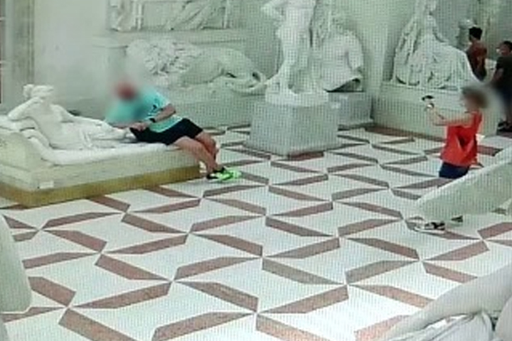 An Austrian man, left, leans on a plaster cast model at a museum in Italy on July 31, 2020.