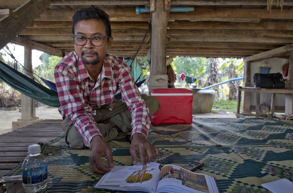 Vannak Anan Prum, who was double trafficked, points to his illustration of an abusive former boss, a palm oil estate owner, in his graphic novel depicting his life as a slave on a fishing boat before being sold onto a Malaysian palm oil plantation, at his home in Pursat, Cambodia, Saturday, March 30, 2019