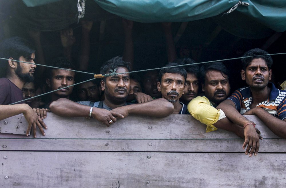 Men from Bangladesh ride in the back of a truck heading to an immigration detention center in Medan, North Sumatra, Indonesia, Wednesday, Feb. 6, 2019. Officials said a few dozen men were found locked in a house, waiting for a broker to bring them illegally by boat to Malaysia, with some planning to work on palm oil plantations.