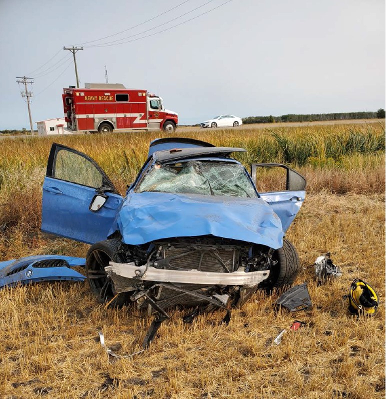 A severely damaged BMW sedan sits in the ditch on Highway 2, east of St. Claude on Monday. RCMP say the driver was racing another vehicle when he lost control.