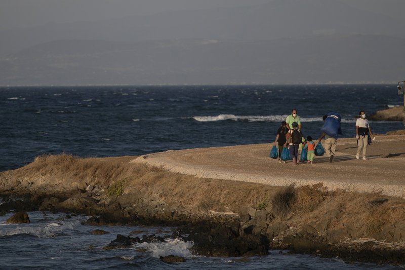 Migrants with their belongings walk near the new temporary refugee camp in Karatepe near Mytilene town, on the northeastern island of Lesbos, Greece, Monday, Sept. 14, 2020. Greece's prime minister demanded Sunday that the European Union take a greater responsibility for managing migration into the bloc, as Greek authorities promised that 12,000 migrants and asylum-seekers left homeless after fire gutted an overcrowded camp would be moved shortly to a new tent city. 
