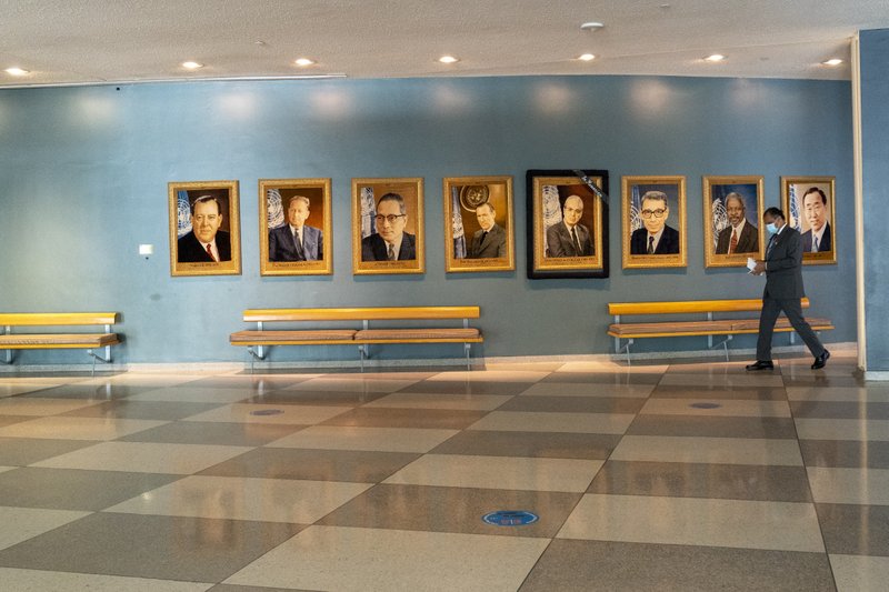 A man walk past portraits of former United Nations Secretary-Generals, Monday, Sept. 21, 2020 at United Nations headquarters.