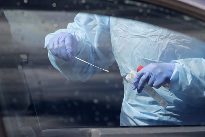 A medical assistant prepares to take a swab from a patient at a drive-thru and walk-up coronavirus testing site in this file photo.