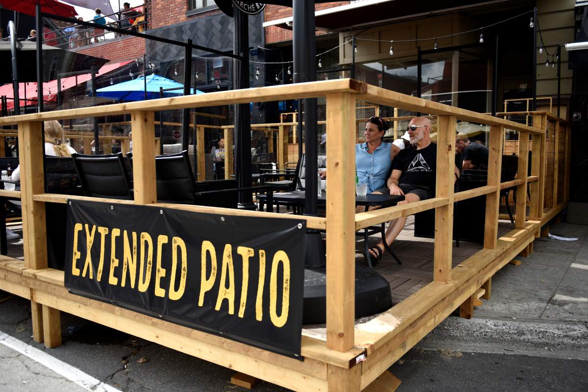 People sit on a bar's patio built on top of the sidewalk and street parking spaces, in the ByWard Market in Ottawa, on Sunday, July 12, 2020, in the midst of the COVID-19 pandemic.