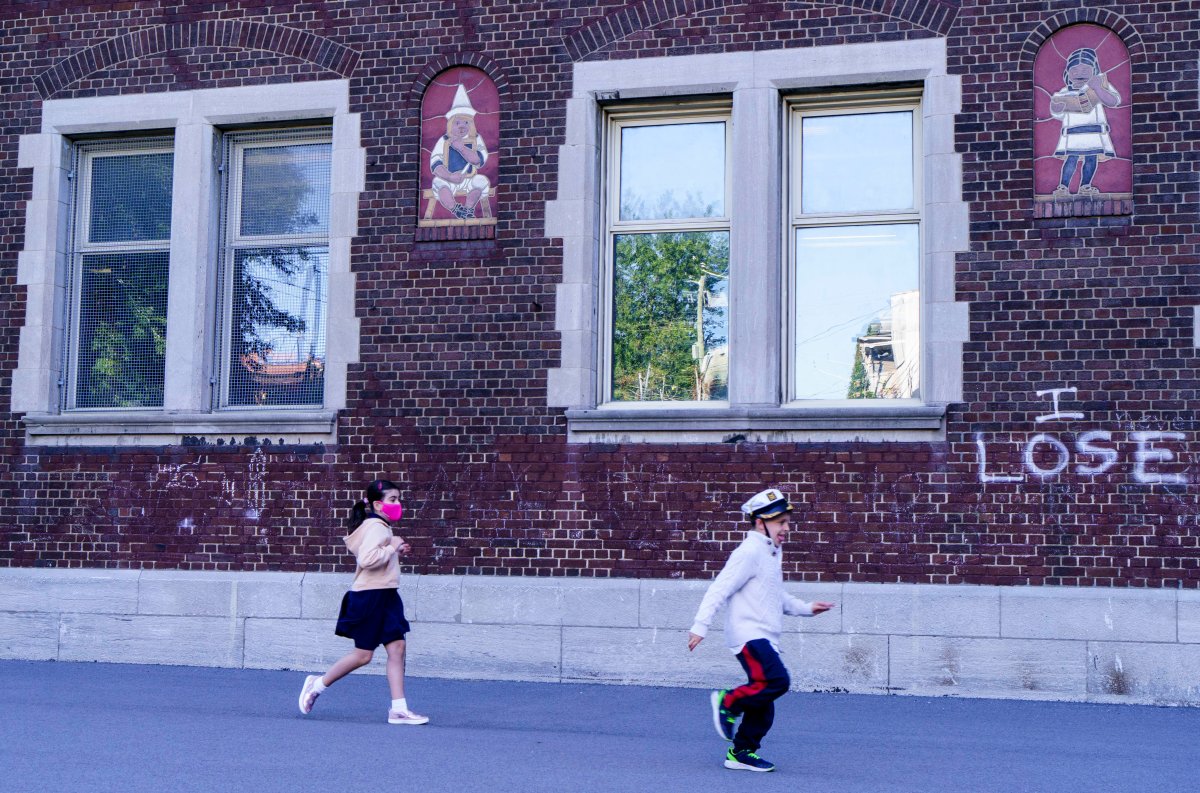 Two young students play in the school yard at the Bancroft Elementary School as students go back to school in Montreal, on Monday, August 31, 2020. 