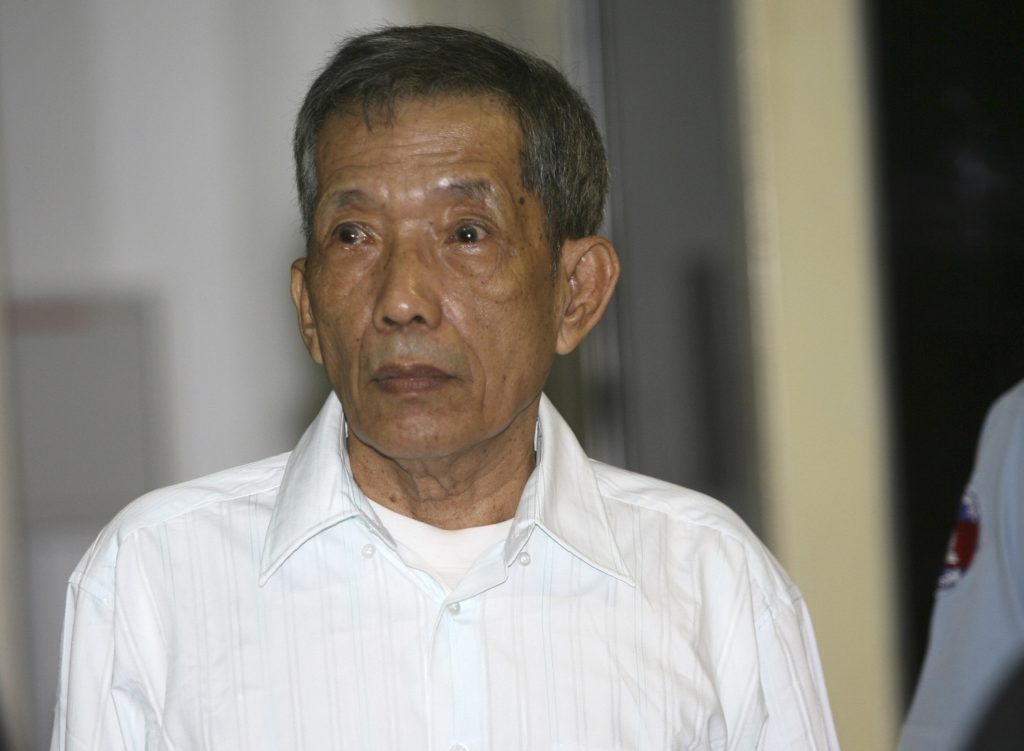 FILE - In this March 30, 2020, file photo, former Khmer Rouge prison chief Kaing Guek Eav, also know as Duch, looks on during the first day of a U.N.-backed tribunal in Phnom Penh, Cambodia. The Khmer Rouge’s chief jailer, who admitted overseeing the torture and killings of as many as 16,000 Cambodians while running the regime’s most notorious prison, died at a hospital in Cambodia early Wednesday morning, Sept. 2, 2020. Kaing Guek Eav, known as Duch, was 77 and had been serving a life prison term for war crimes and crimes against humanity. 