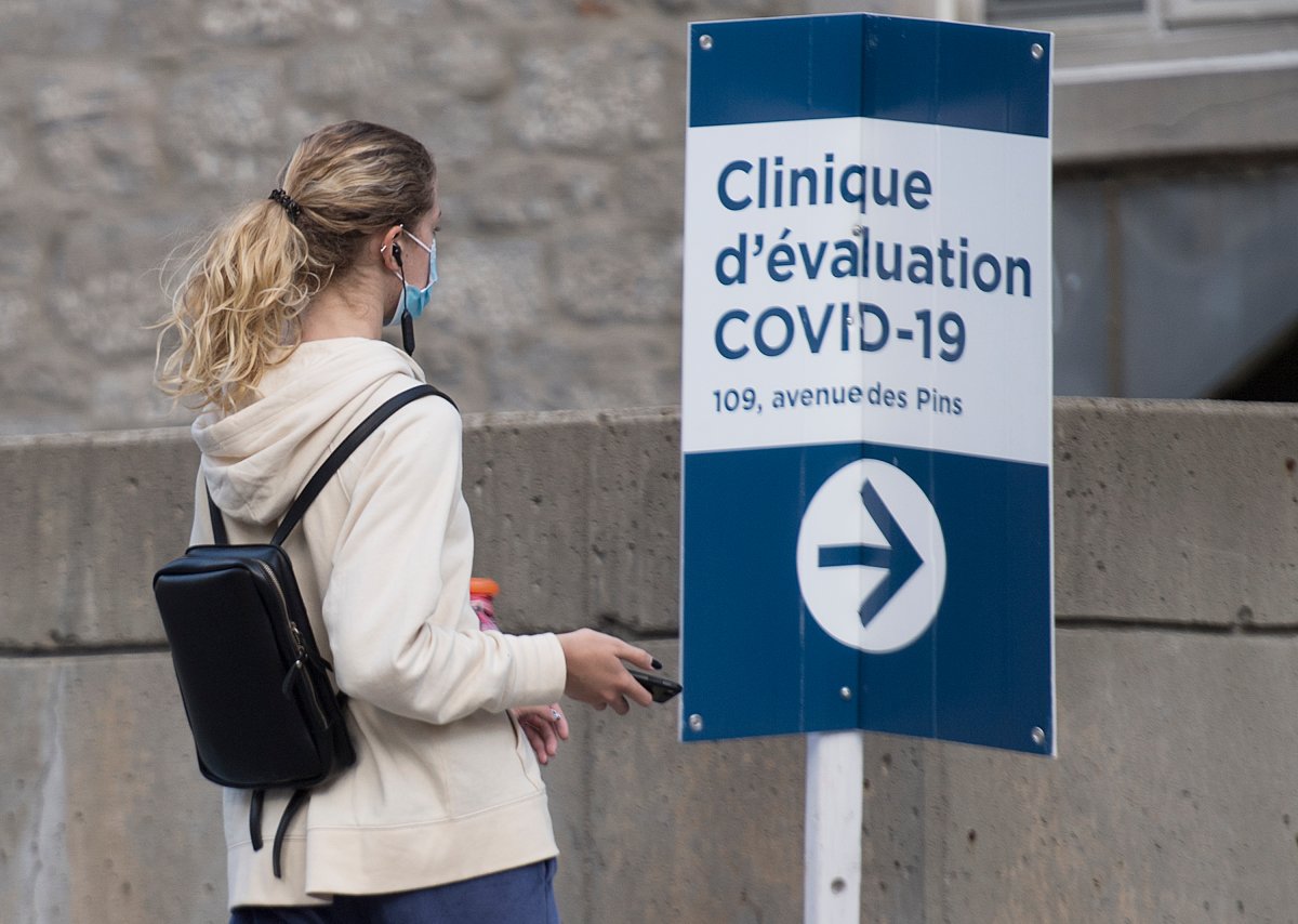 A woman wears a face mask as she walks by a sign for a COVID-19 testing clinic in Montreal, Saturday, Sept. 5, 2020, as the COVID-19 pandemic continues in Canada and around the world. 