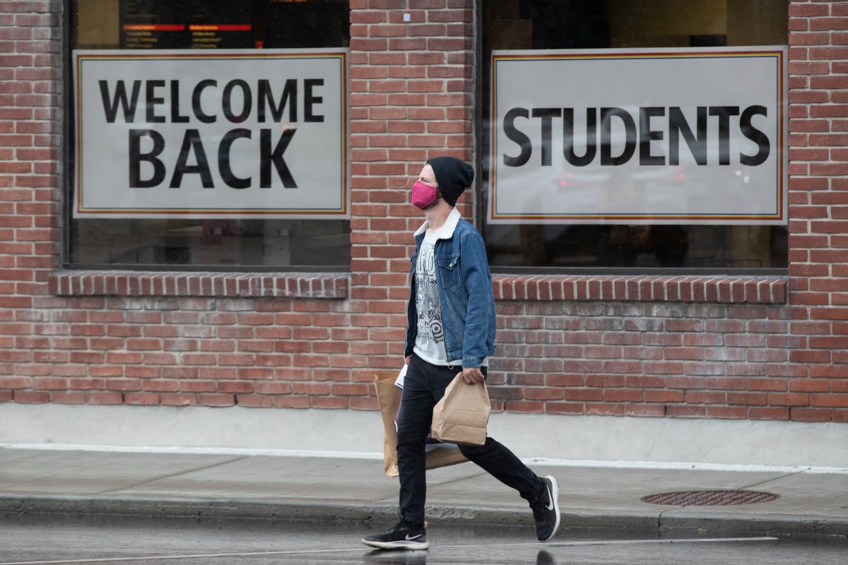 A person walks with a masks by posters welcoming students back to school in Kingston, Ontario on Tuesday, Sep 8, 2020. 