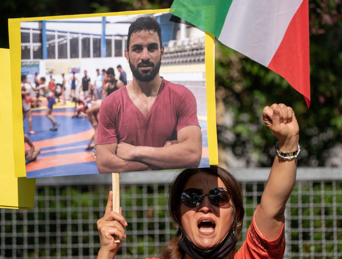A supporter of the National Council of Resistance Iran (NWRI) and the Iranian Exile Society in Berlin holds a placard with the picture of Iranian wrestler Navid Afkari, while protesting against his execution at the Iranian embassy in Berlin, Germany, Sept. 12, 2020.