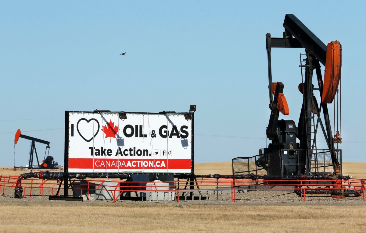 A sign supporting the oil and gas industry beside two oilfield pumpjacks pumping crude along the Trans-Canada Highway near Brooks, Alta., on Sept. 11, 2020.