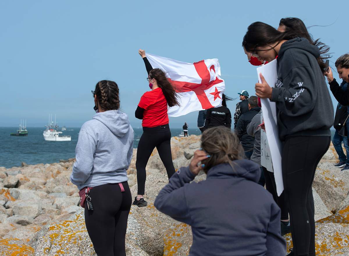 Members of the Sipekne'katik First Nation, supported by other First Nations, stand on the breakwater in Saulnierville, N.S.,  as non-indigenous boats protest the launch the Mi'kmaq self-regulated fishery on Thursday, Sept. 17, 2020. The First Nation says a 1999 Supreme Court of Canada ruling, known as the Marshall decision, granted the Mi'kmaq the right to catch and sell lobster outside of the regular fishing season. THE CANADIAN PRESS/Andrew Vaughan.