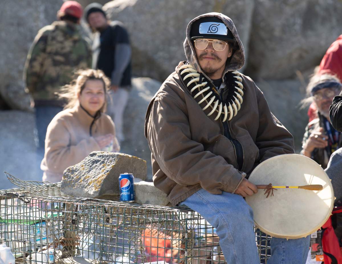 A Sipekne’katik First Nation community member holds a drum as he sits on lobster traps in Saulnierville, N.S. on Sunday, September 20, 2020. A flotilla of non-Indigenous fishing boats moved into St. Marys Bay off western Nova Scotia on Sunday to remove lobster traps set by fishermen from the Sipekne’katik First Nation. THE CANADIAN PRESS/Mark O’Neill