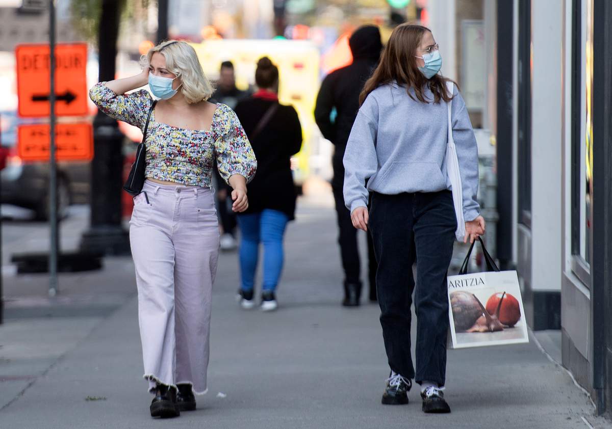 People wear face masks as they walk along a street in Montreal, Monday, September 21, 2020, as the COVID-19 pandemic continues in Canada and around the world. 