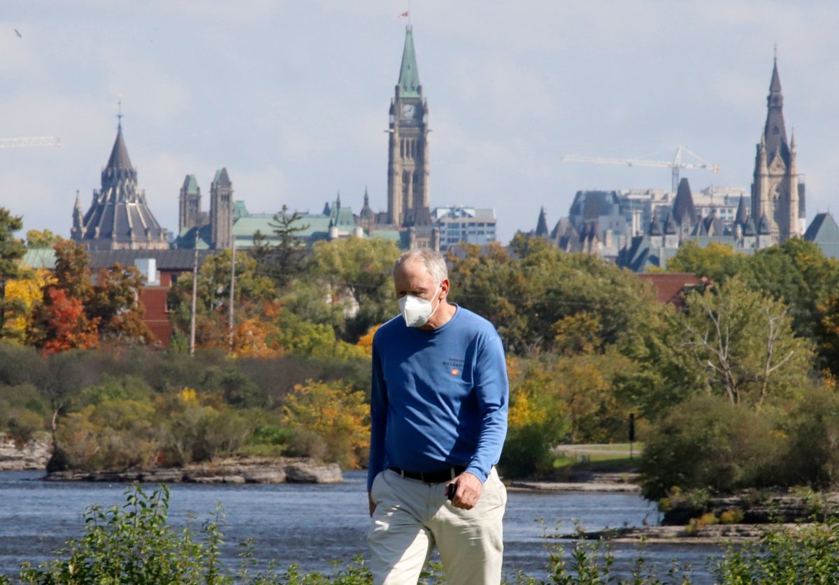 A man wearing a mask walks in front of the Parliament Buildings during the COVID-19 pandemic in Ottawa on Monday, Sept. 28, 2020.