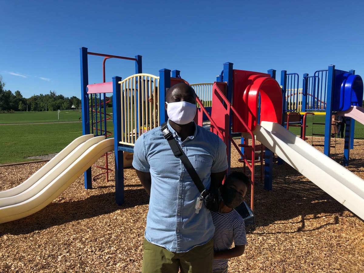 High school teacher Kwame Aidoo and his son stand in a playground behind White Oaks Public School in London, Ont.