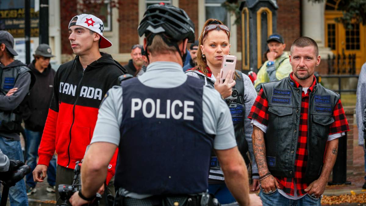 A police officer stands between counter-protesters and demonstrators as they march down a street during an anti-racism event in Red Deer, Alta., Sunday, Oct. 4, 2020.
