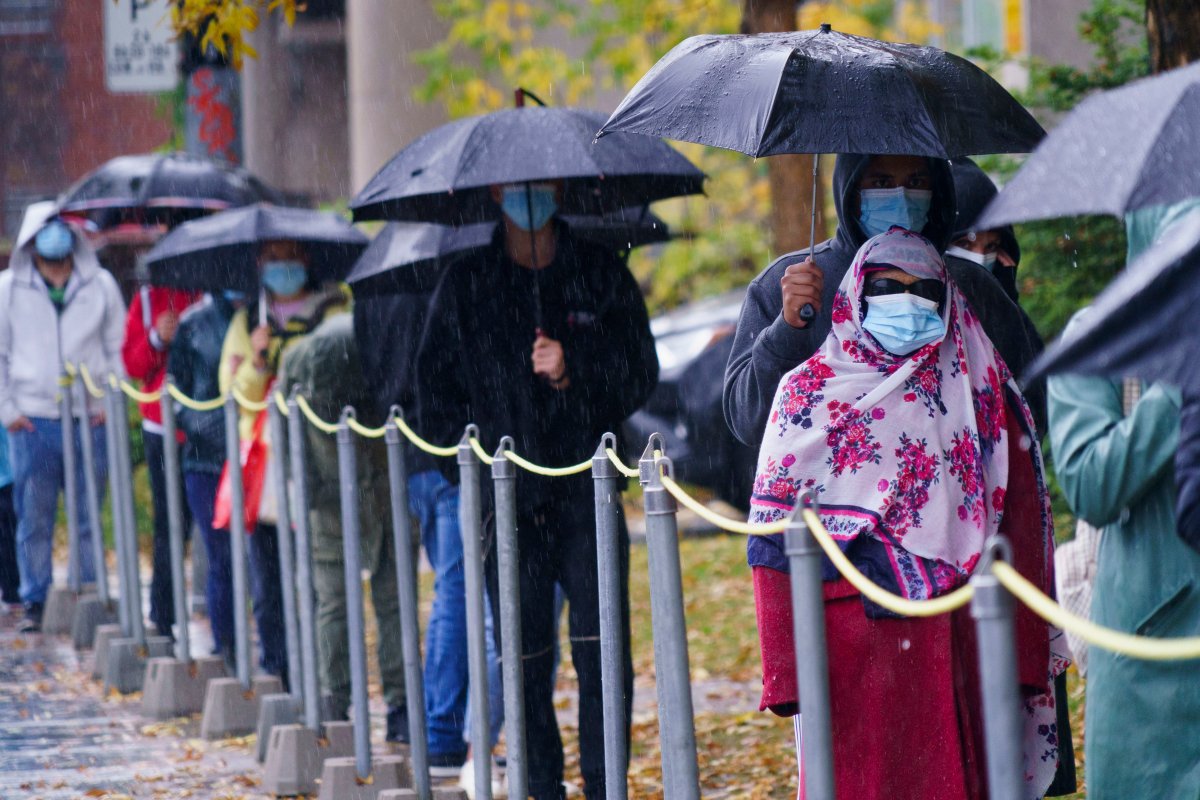 People wait in line in the pouring rain outside a walk-in COVID-19 test clinic in Montreal, on Wednesday, Oct. 7, 2020. 