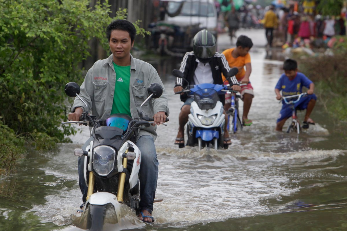 Local villagers travel through a flooded road following recent rains on the outskirts of Phnom Penh , Cambodia, Oct. 11, 2020.
