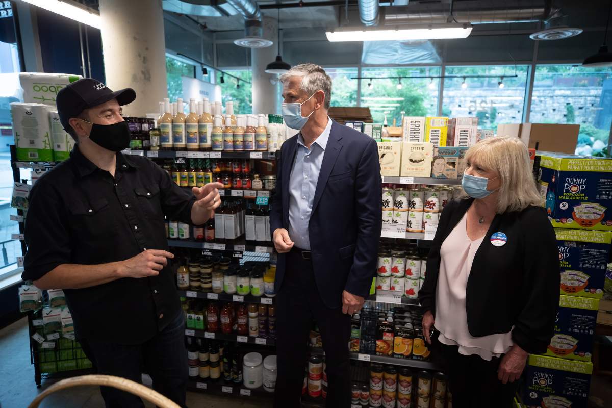 Liberal Leader Andrew Wilkinson, centre, and local candidate Jane Thornthwaite, right, listen to Larry's Market owner Ryan Dennis during a campaign stop at the grocery store, in North Vancouver, on Sunday, October 4, 2020. A provincial election will be held in British Columbia on October 24. 