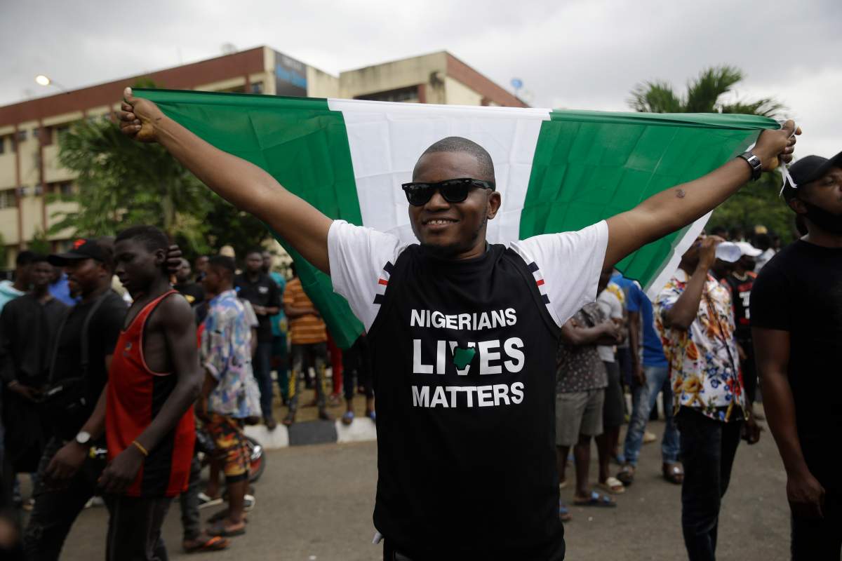 A man holds a Nigerian flag as he demonstrates on the street to protest against police brutality in Lagos, Nigeria, Oct. 16, 2020.
