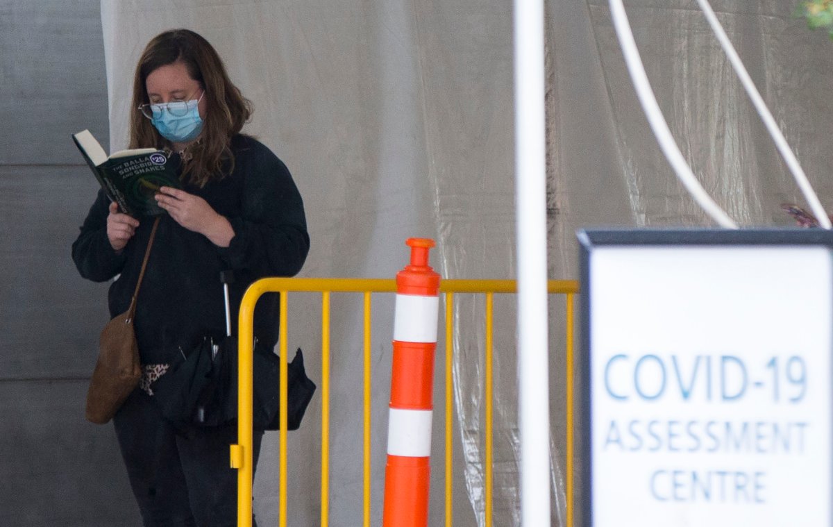 TORONTO, Oct. 15, 2020 A woman wearing a face mask reads a book as she waits for COVID-19 test outside a COVID-19 assessment center in Toronto, Canada, on Oct. 15, 2020.