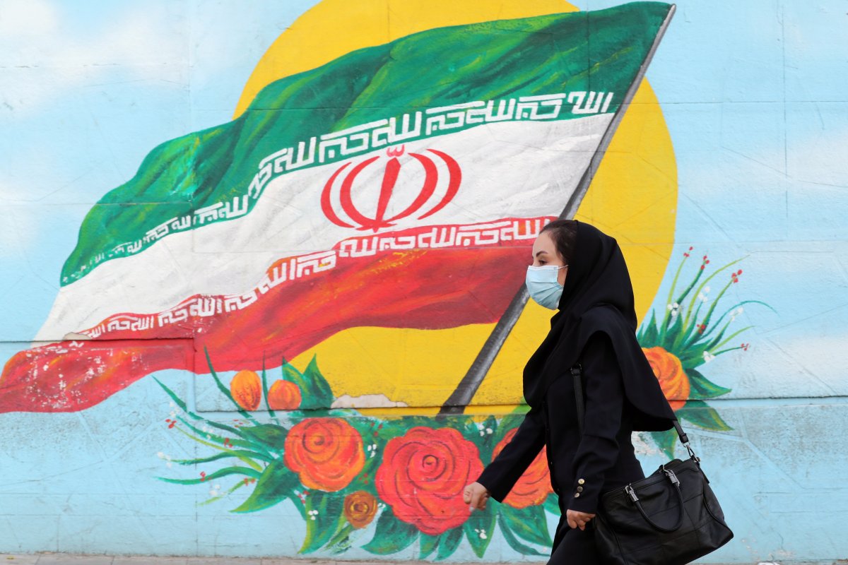 A woman walks past an Iranian flag painted on a wall in Tehran, Iran, 19 October 2020. EPA/ABEDIN TAHERKENAREH.