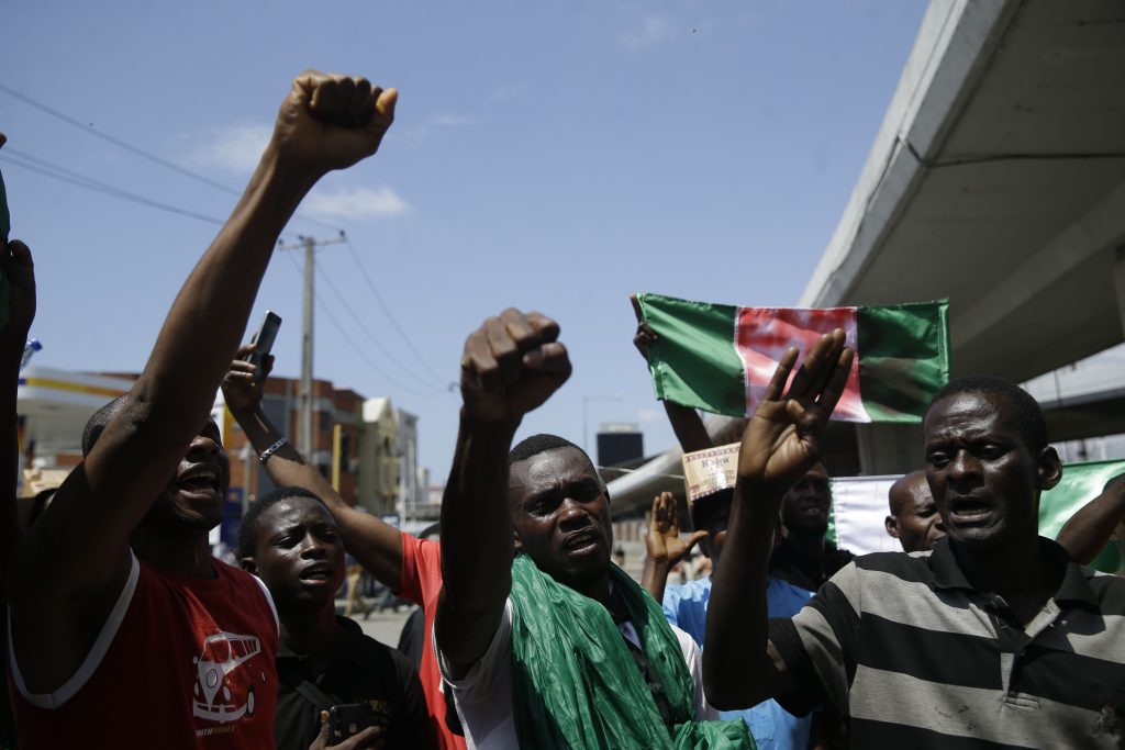 People hold banners as they demonstrate on the street to protest against police brutality, in Lagos, Nigeria, Tuesday Oct. 20, 2020. After 13 days of protests against police brutality, authorities have imposed a 24-hour curfew in Lagos, Nigeria's largest city as moves are made to stop growing violence. 