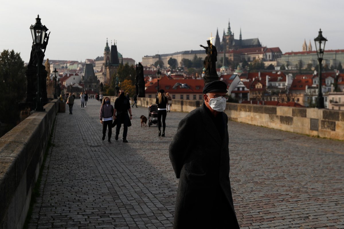 A man wearing a face mask walks across the medieval Charles Bridge in Prague, Czech Republic, Wednesday, Oct. 21, 2020.