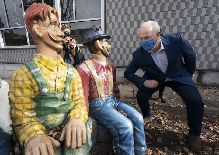 NDP Leader John Horgan pretends to elbow bump a statue as he main streets in Abbotsford, B.C., Wednesday, October 21, 2020.   