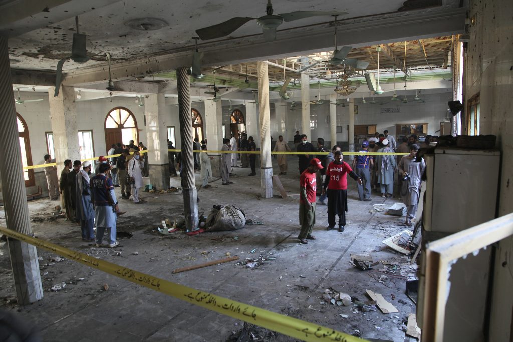Rescue workers and police officers examine the site of a bomb explosion in an Islamic seminary in Peshawar, Pakistan, Tuesday, Oct. 27, 2020. A powerful bomb blast ripped through the Islamic seminary on the outskirts of the northwest Pakistani city of Peshawar on Tuesday morning, killing some students and wounding dozens others, police and a hospital spokesman said. 