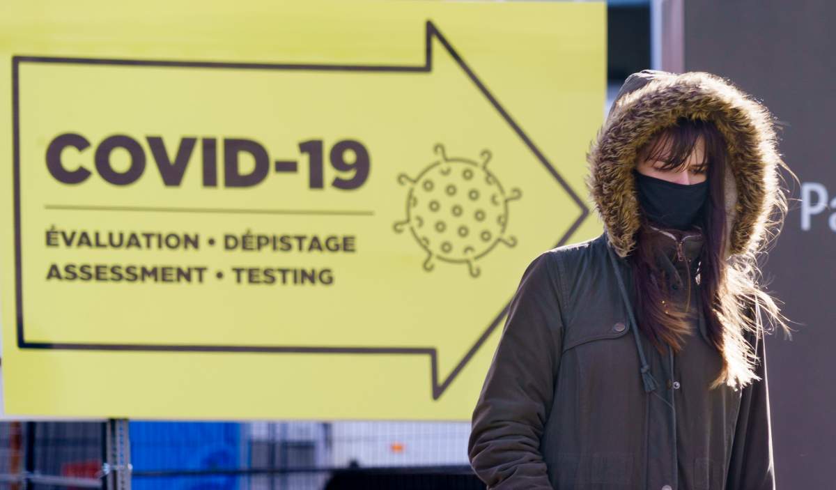 A woman all bundled up walks past a COVID-19 test clinic during a brisk morning in Montreal, on Friday, October 30, 2020. 