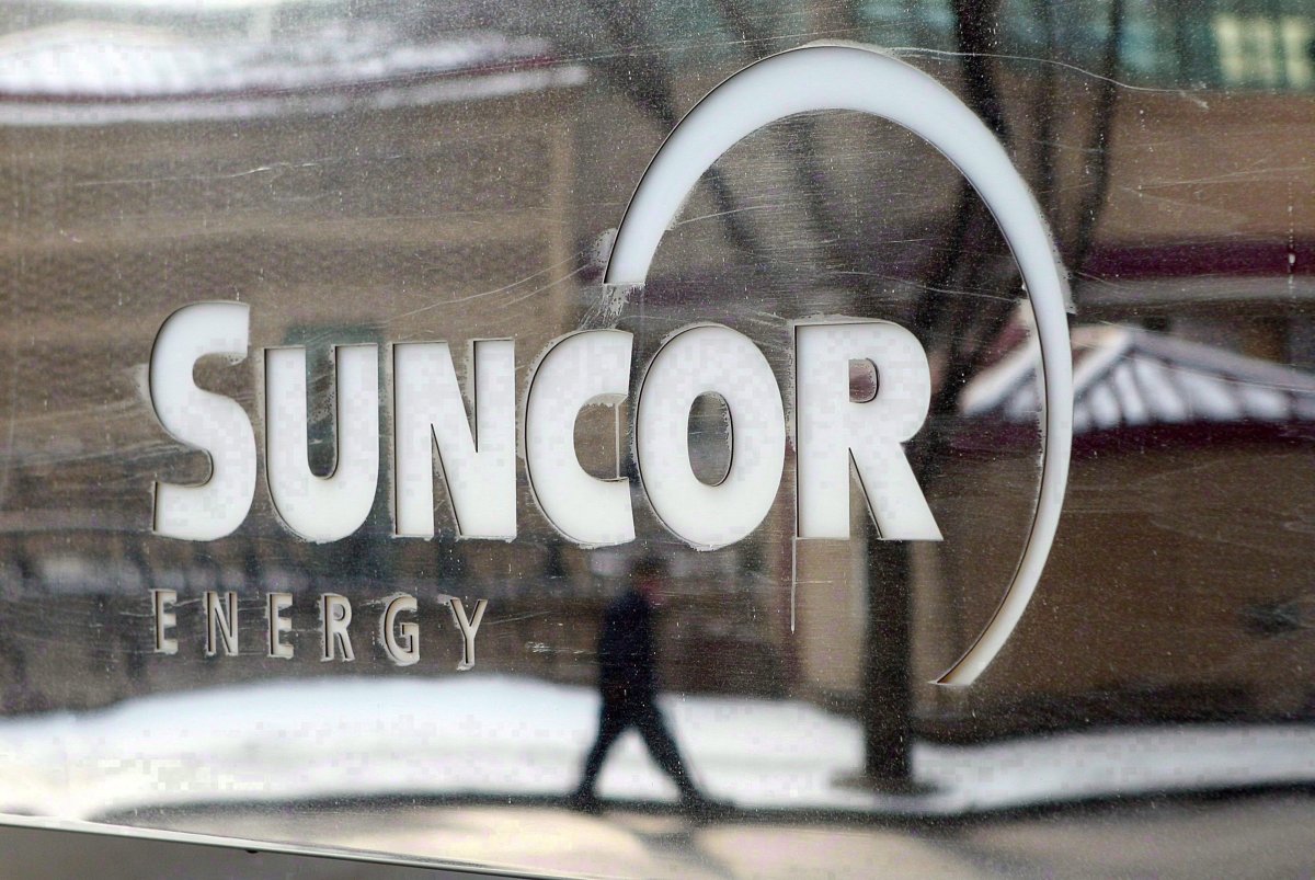 A pedestrian is reflected in a Suncor Energy sign in Calgary, Monday, Feb. 1, 2010.